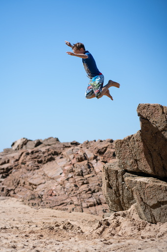 Alastair jumping off rocks at Plemont